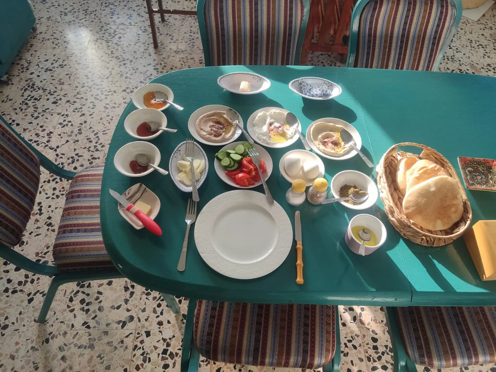 فطور فلسطيني بأطباق صغيرة وبيض وخبز طازج على طاولة فيروزية
